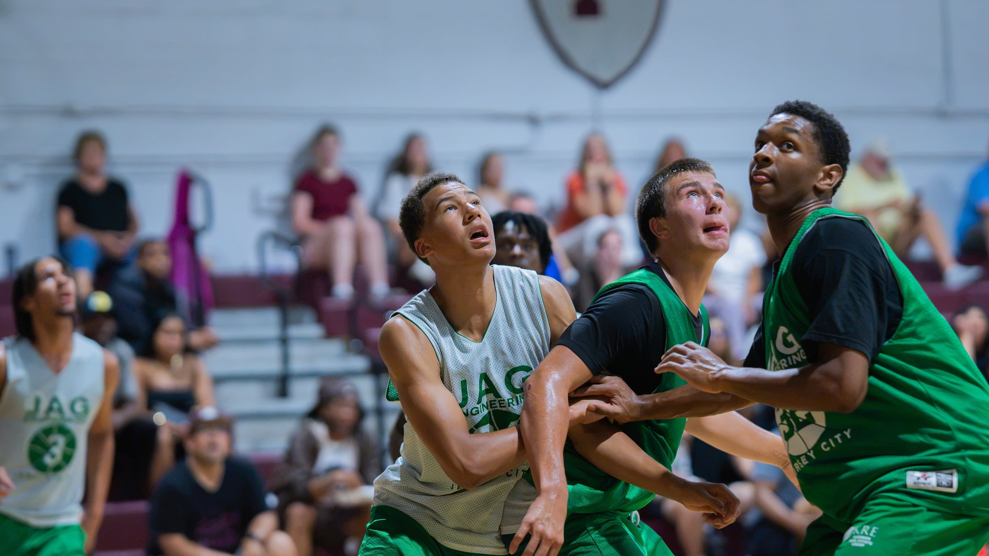 Three players boxing out, every face turned up to the ball