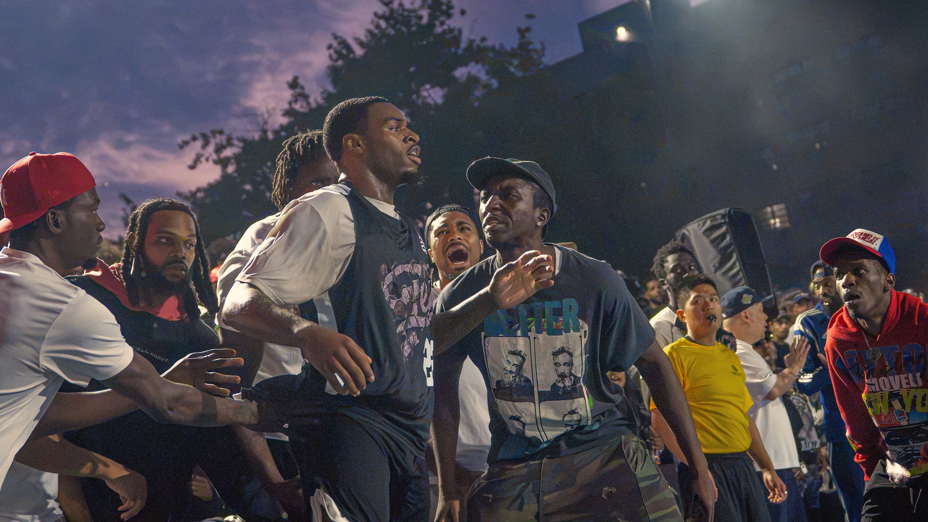 The sideline erupts as the shot drops, dusk over the park