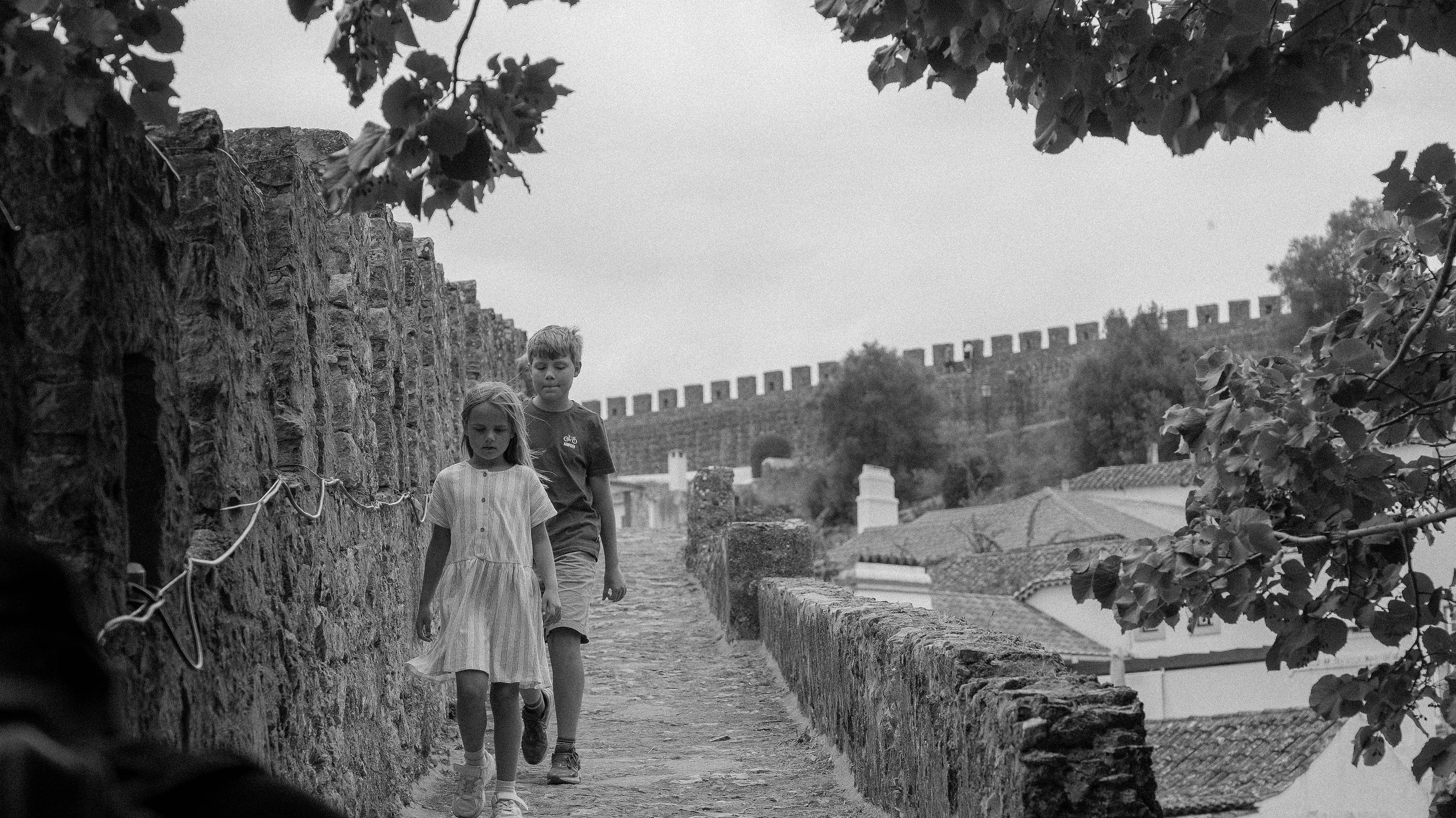 A child walking beside an old stone wall
