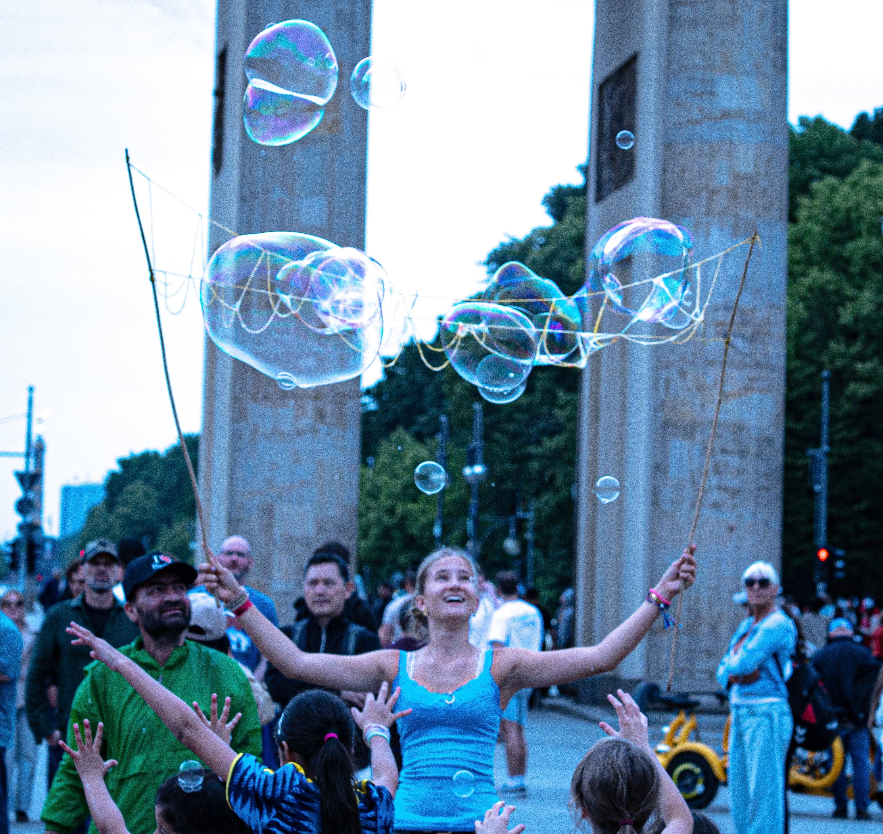 A performer holding up wands trailing soap bubbles at the Brandenburg Gate