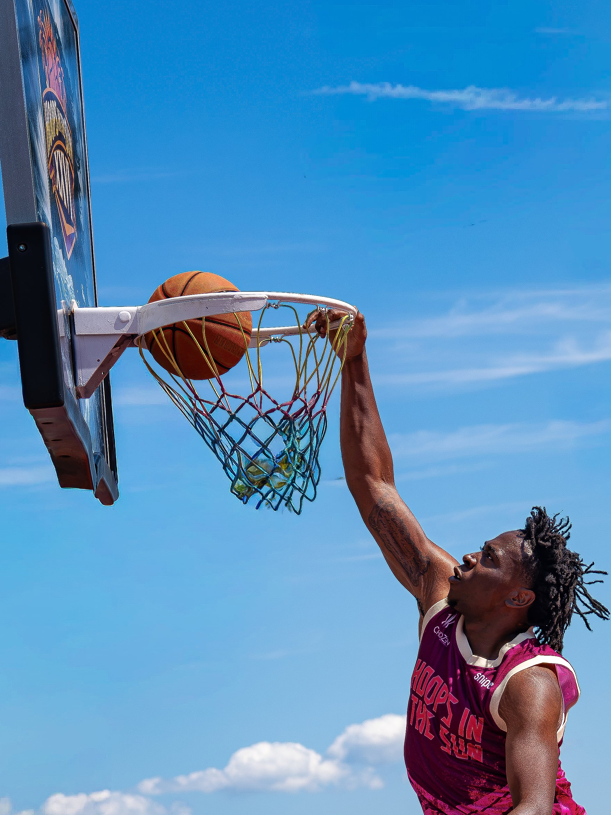 Hanging on the rim after the dunk, midday sun