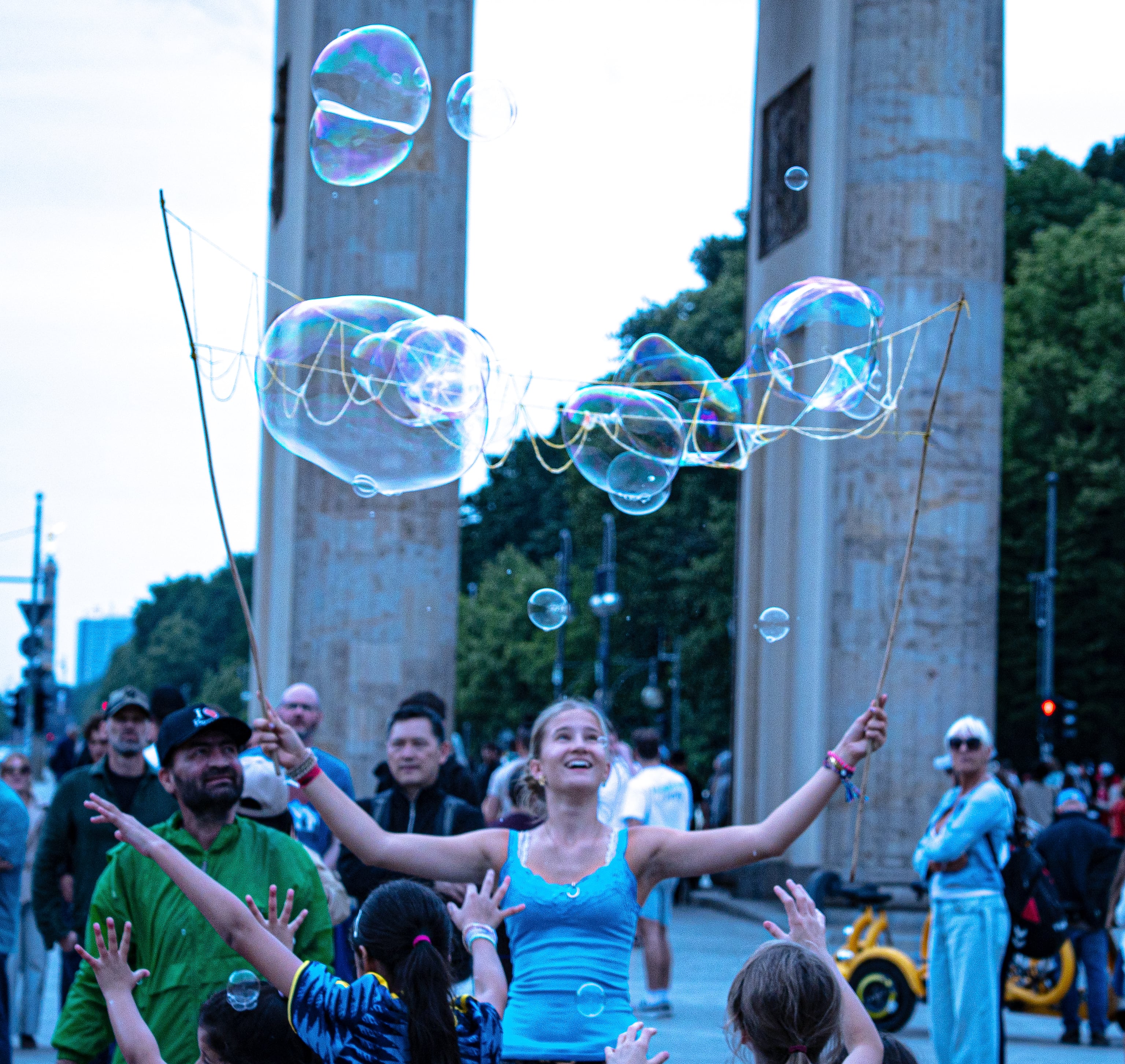 A performer holding up wands trailing soap bubbles at the Brandenburg Gate